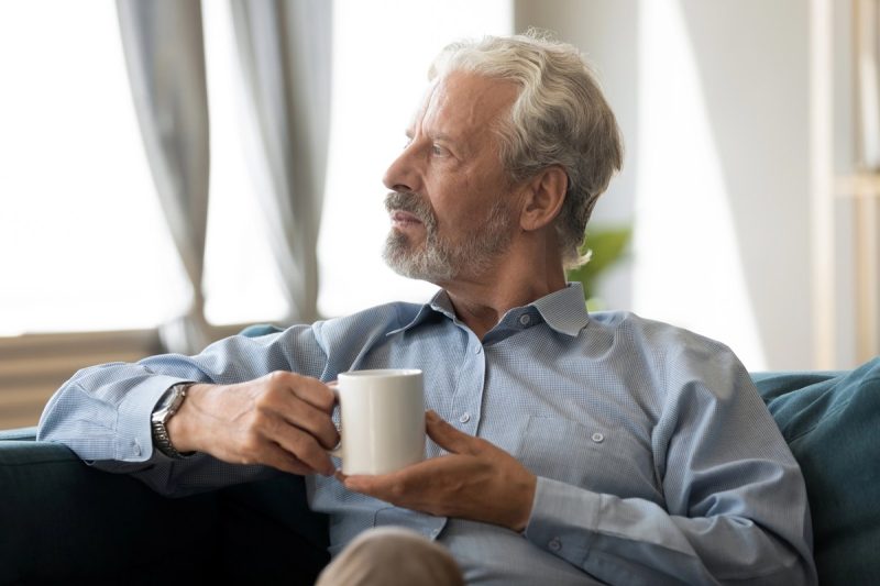 older man thinking while resting on comfortable sofa with coffee